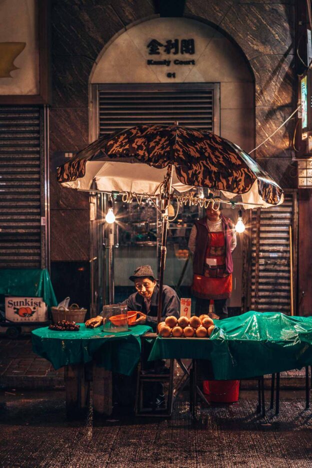 An elderly gentlemen with a bucket hat packs up his stall at night market in Mong Kok, Hong Kong