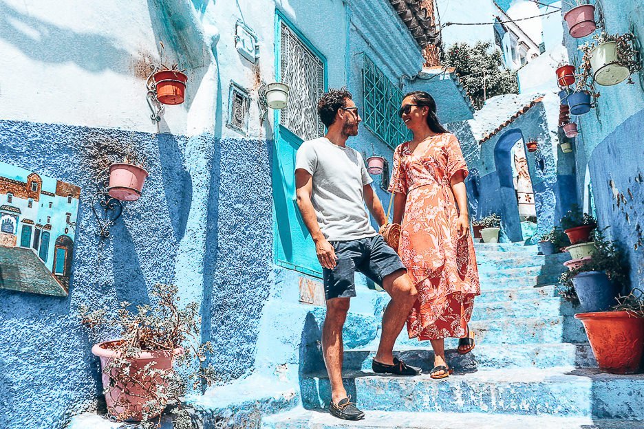 A couple stand on stairs among potted plants in Chefchaouen, Morocco - 5 Things When Dating Travelling