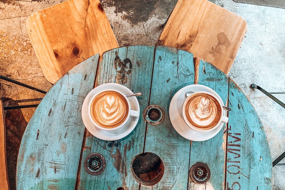 Large flat white and mint mocha on a faded blue wooden table at The Brew Job Coffee, Kowloon, Hong Kong