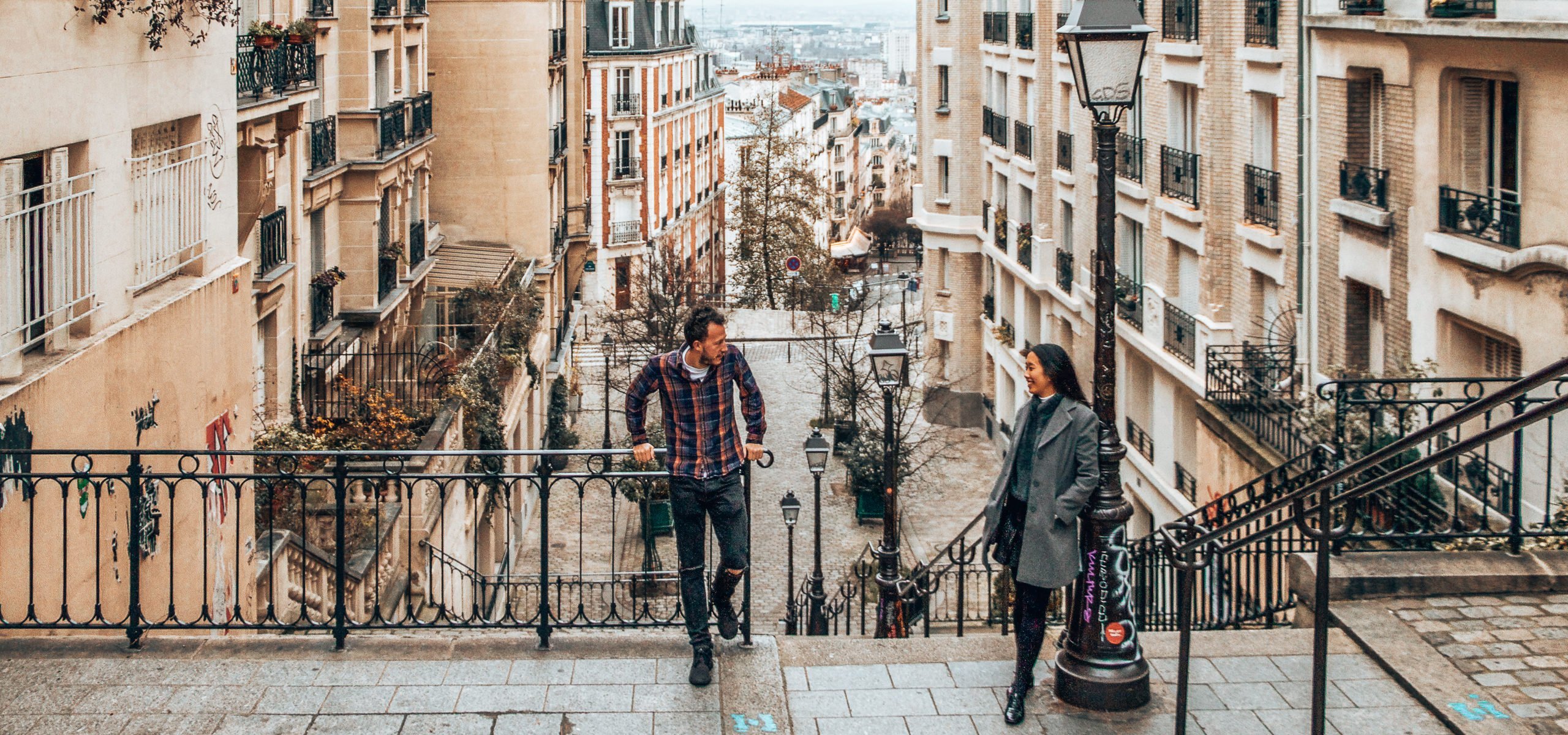 A couple stand on the top of stairs in Montmartre, Paris
