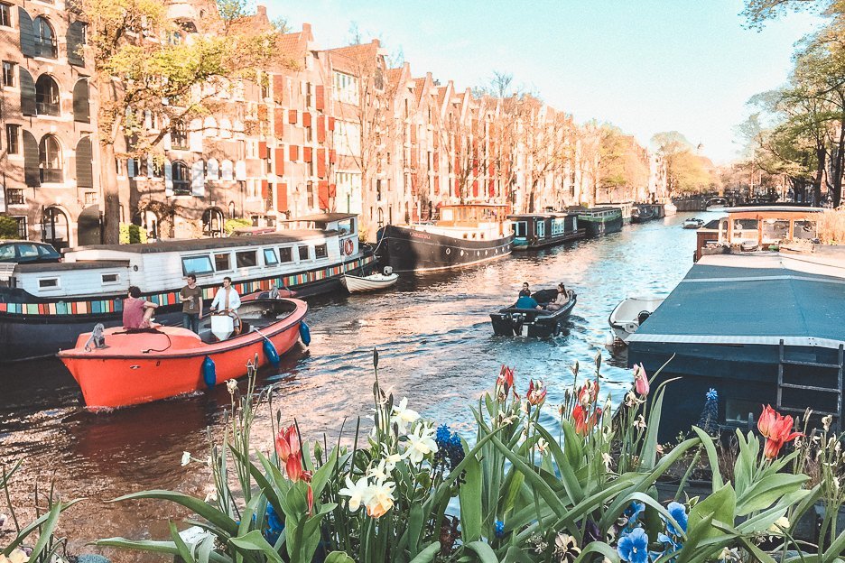 A Non Touristy Weekend Guide To Amsterdam 13 L Houseboats and flowers along a canal in Amsterdam, The Netherlands