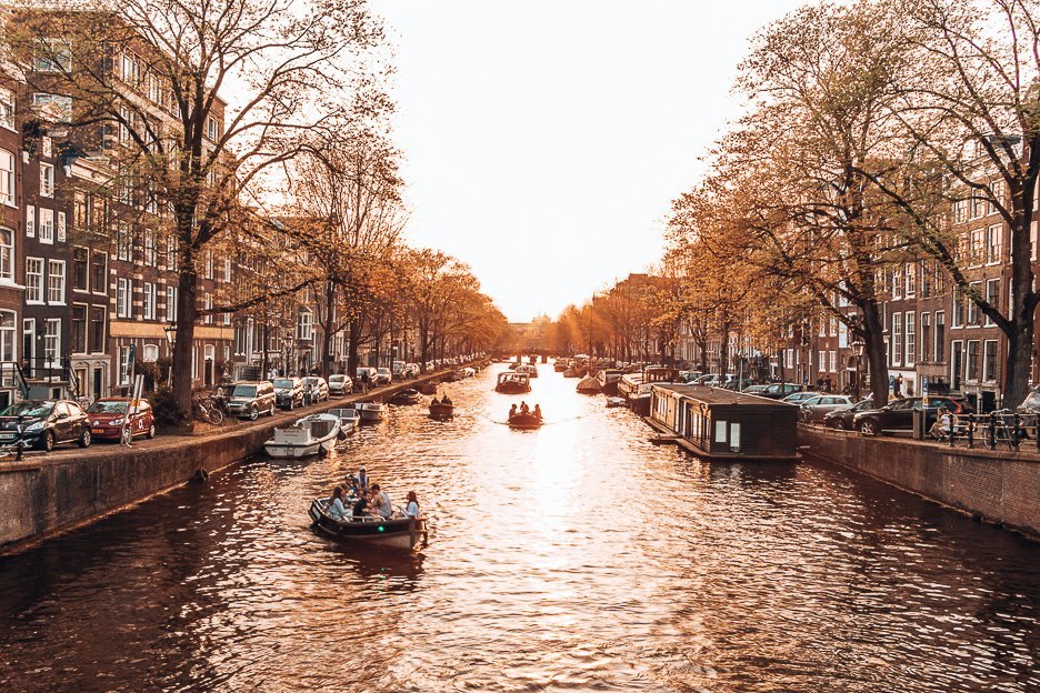 A Non Touristy Weekend Guide To Amsterdam 14 L Boats cruise along the canals during sunset in Amsterdam, The Netherlands