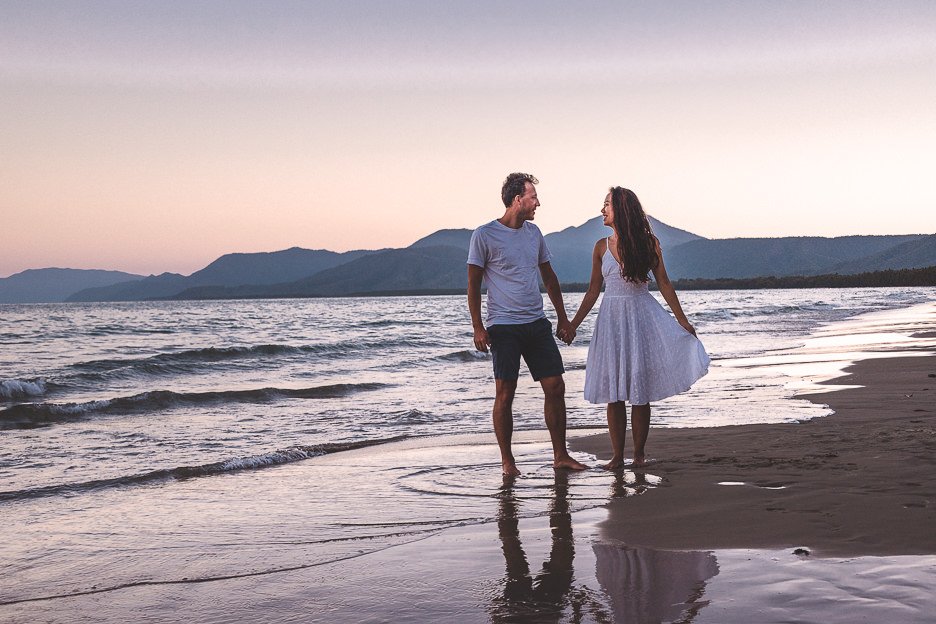 A couple hold hands on Four Mile Beach at sunset in Port Douglas, tropical North Queensland