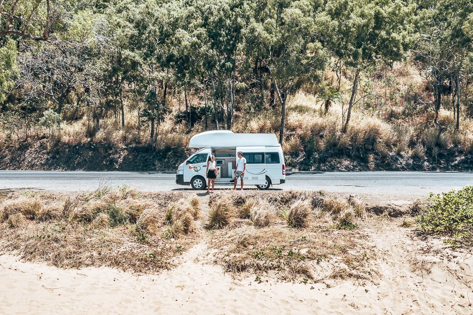 A couple stand in front of a Britz campervan on the Captain Cook Highway in Tropical north Queensland