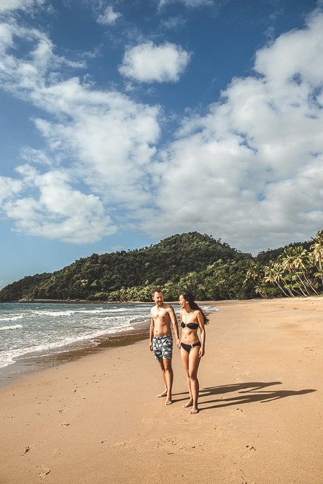 A couple walk along the beach at Bingil Bay, tropical north Queensland