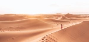 Jasmine walks along the peaks of a sand dune at sunset in the Sahara Desert, Morocco