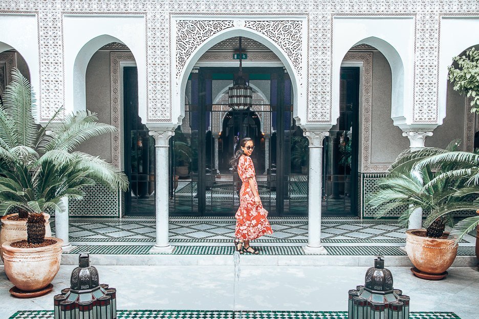 A woman in a red dress twirls in the outdoor courtyard of La Mamounia, Marrakech, Morocco