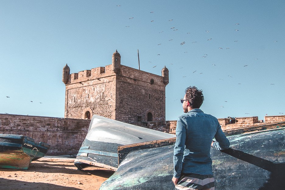 Morocco Travel Photography 35 Photos To Inspire You To Visit 19 L Bevan stands next to upturned blue fishing boats at Port of Essaouira, Morocco