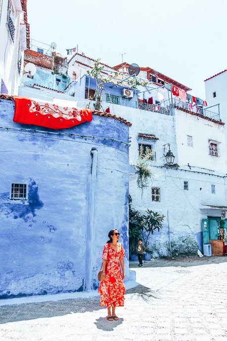 Morocco Travel Photography 35 Photos To Inspire You To Visit 30 P A woman dressed in a red dress stands in an empty square in Chefchaouen, Morocco
