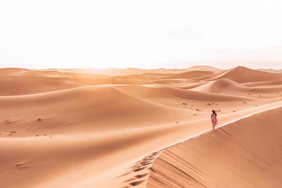 Morocco Travel Photography 35 Photos To Inspire You To Visit 6 L A woman in a red dress walks on the edge of a sand dune in the Sahara Desert, Morocco
