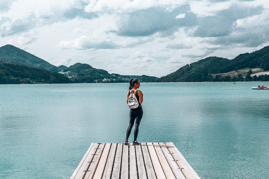 Planning A European Road Trip What You Should Know Before You Go 3 L Jasmine stands on a pier looking out over a lake at Fuschal Am See, Austria