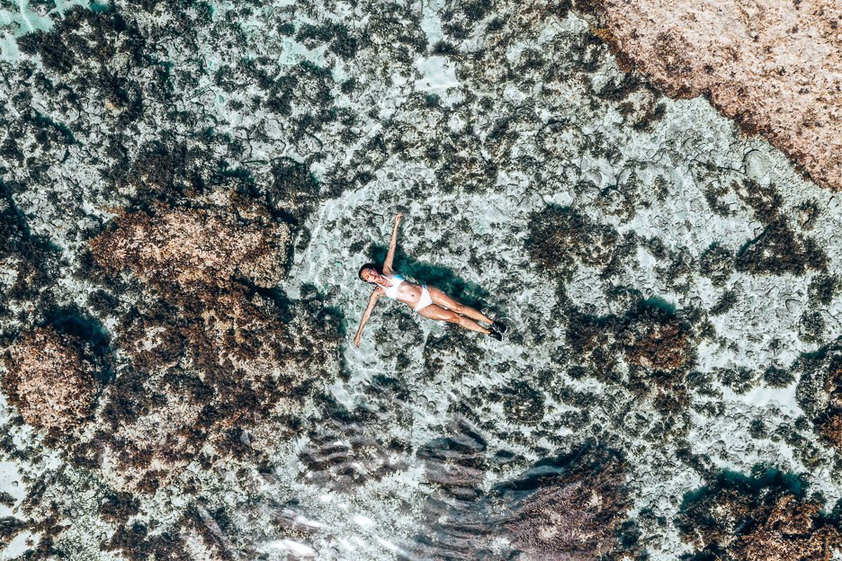 A girl in a white bikini floats on her back in a tidal pool at Magpupungko, Siargao