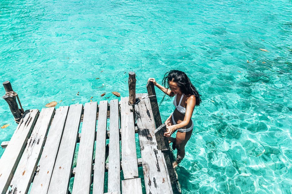 Siargao Itinerary And A girl steps down the ladder into the water at Sugba Lagoon, Siargao