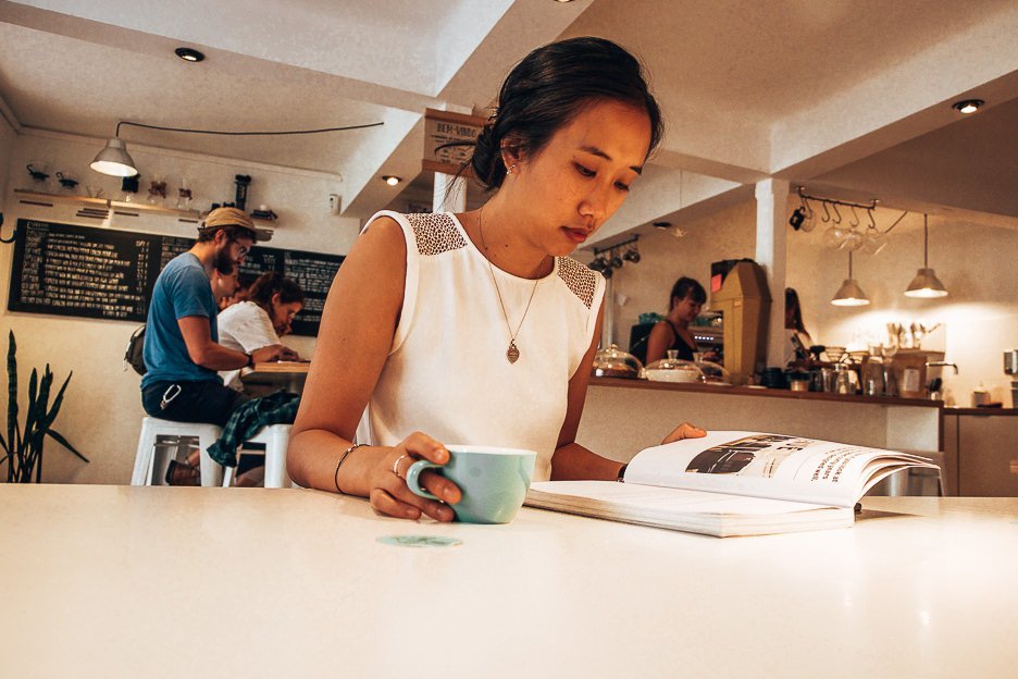 Jasmine reading a magazine and drinking coffee at Copenhagen Coffee Lab, Lisbon Portugal