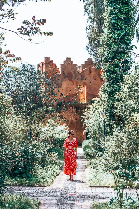 A woman in a red dress stands in the garden of the kasbah, Chefchaouen Morocco