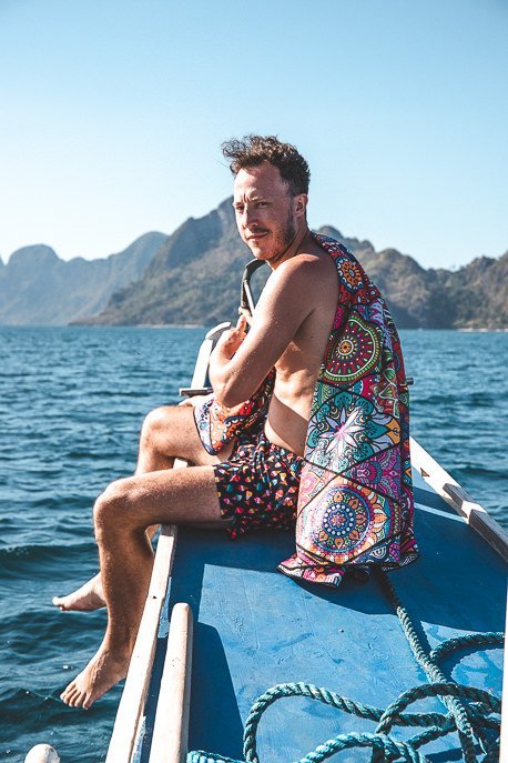 The Ultimate Beach Packing List 3 P Bevan sits on the edge of the boat with his Tesalate towel, Private Boat Tour in El Nido