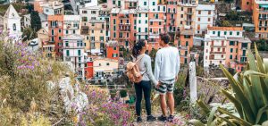 A couple holds hands overlooking the colourful houses of Manarola, Cinque Terre