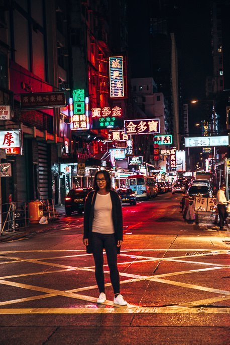 Jasmine standing in the middle of the street with neon lights behind her, Mong Kok