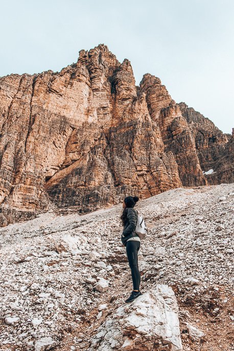 What To Pack For A European Road Trip 6 P Jasmine stands on a rock looking up at the peaks of Tre Cime di Lavaredo in The Dolomites, Italy