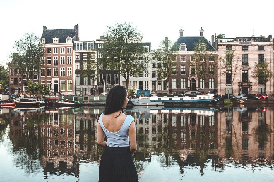 A woman stands next to a canal in Amsterdam, the Netherlands