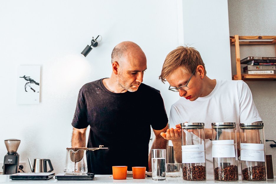 Two male baristas examine coffee beans in Crooked Nose & Coffee Stories cafe in Vilnius, Lithuania