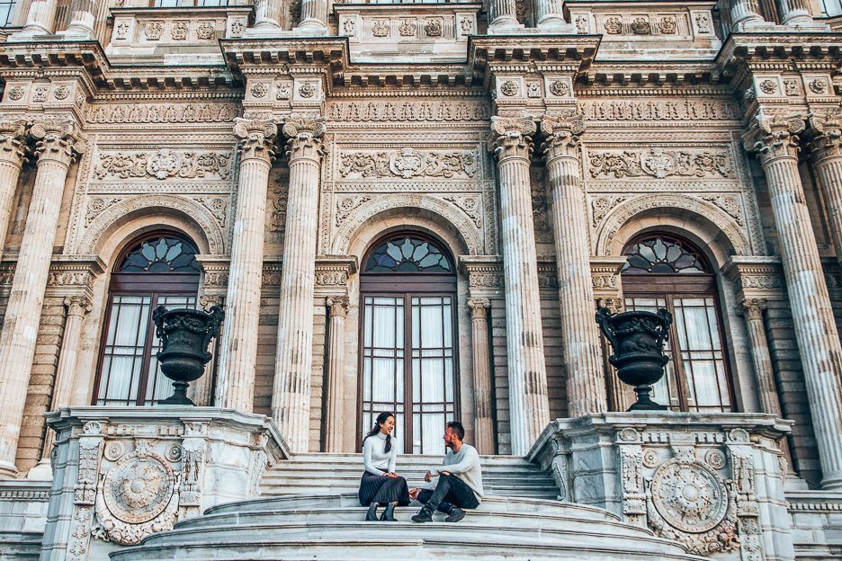 A couple sit on the stairs in front of Dolmabahçe Palace in Istanbul, Turkey