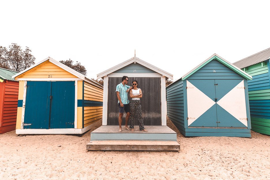 A couple pose in front one of the Brighton Bathing Boxes, Melbourne Victoria