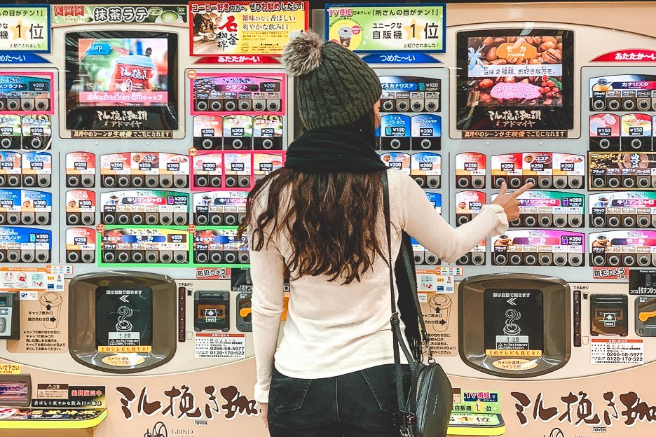 A girl presses a button for coffee from a Japanese vending machine