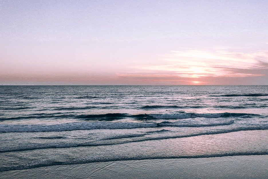 Awesome Day Trips From Brisbane 4.1 L Surfers riding waves during Sunrise at the Gold Coast | Gold Coast day trip ideas
