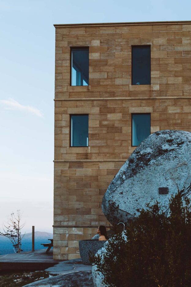 A woman enjoys the outdoor bath among the boulders at The Keep. Tasmania, Australia