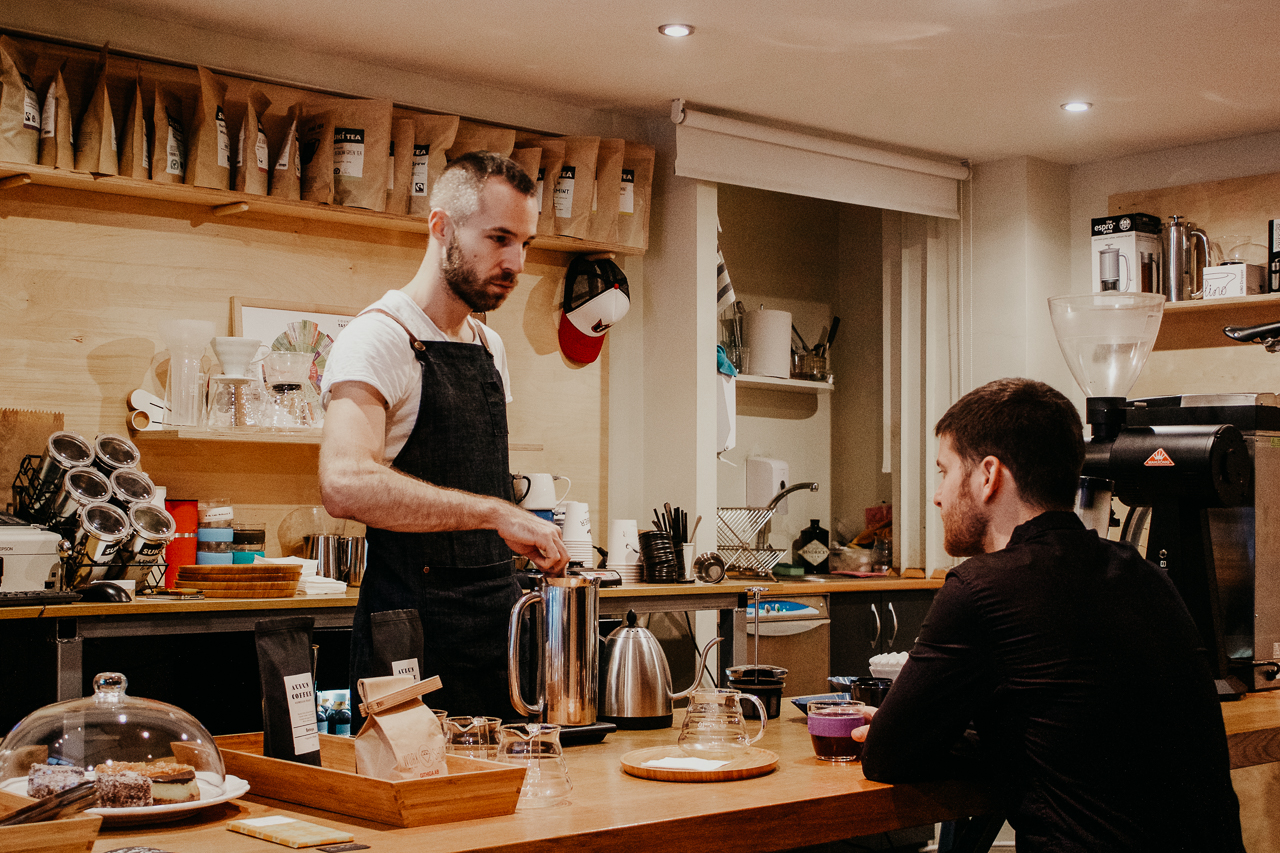 A male barista prepares coffee for a waiting customer at My Little Melbourne Coffee and Brew Bar. Budapest, Hungary