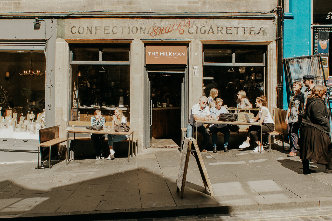 Customers bask in the sunshine on the pavement outside The Milkman cafe. Edinburgh, Scotland