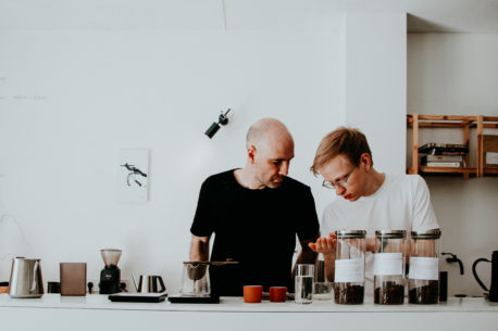 Two baristas examine coffee beans at the counter of Crooked Nose & Coffee Stories cafe. Vilnius, Lithuania